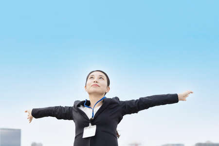 Asian young woman in a suit reaching out and taking a deep breathの写真素材