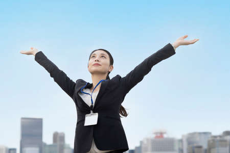 Asian young woman in a suit reaching out and taking a deep breathの写真素材