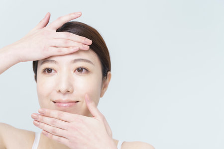 white back ground beauty image / Asian woman touching her faceの写真素材