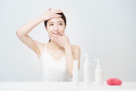 A white bottle with a woman who touches her face for skin careの写真素材