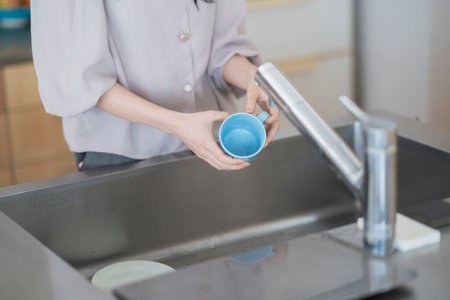 Asian woman washing dishes in the kitchen of the house