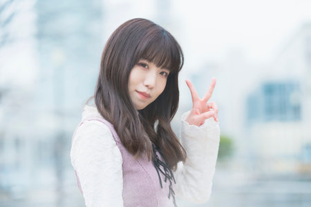 Young asian woman doing a peace sign with a smile outdoorsの写真素材
