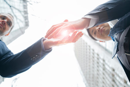 Asian and Caucasian business people shaking hands in suitsの写真素材