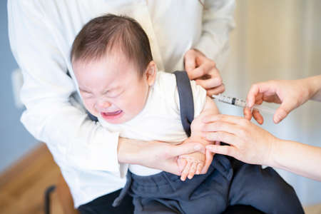 A baby who is vaccinated while being held by her motherの写真素材