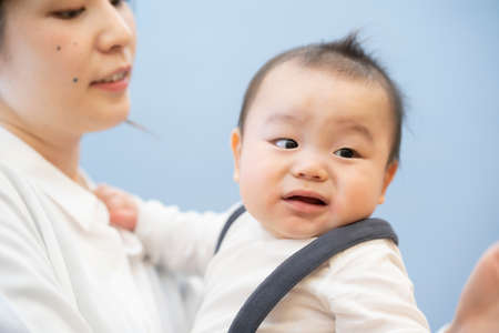 Asian young mom holding a baby with smileの写真素材