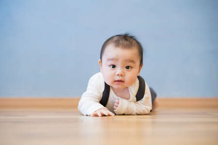 Japanese baby crawling on the wooden floor in the roomの写真素材