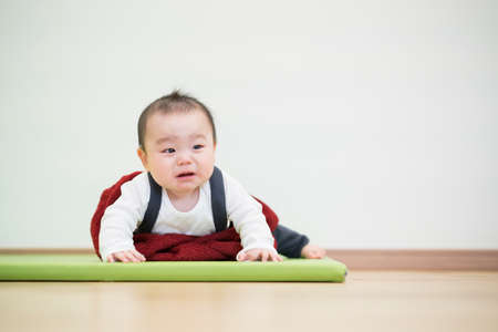 Japanese baby crawling on the wooden floor in the roomの写真素材