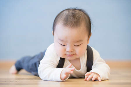 Japanese baby crawling on the wooden floor in the roomの写真素材