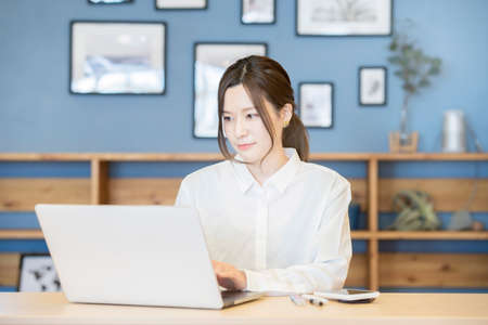 Asian young woman working with laptop in a casual roomの写真素材