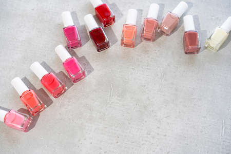 Colorful red and pink nail polish on a gray backgroundの写真素材