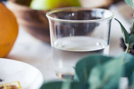 Table photo with glass of water, green, and some fruitsの写真素材