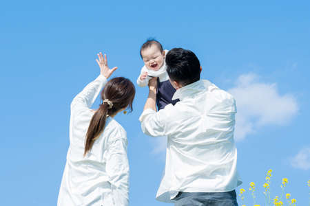 Parents holding their baby high under the blue skyの写真素材