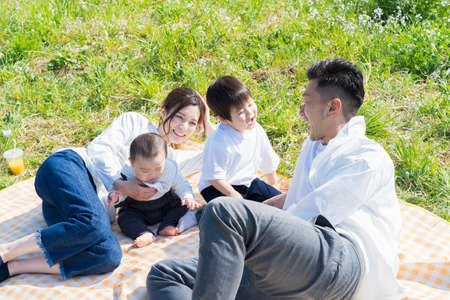Asian parents and children enjoying a picnic on green areaの写真素材