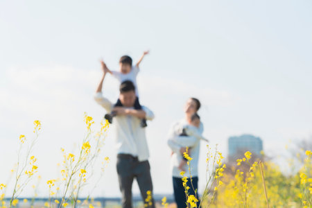Out-of-focus shooting of parents and children walking in the field with a smileの写真素材