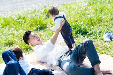 Asian parents and children enjoying a picnic on green areaの写真素材