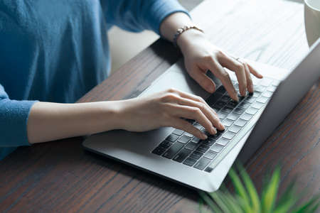 Woman operating a laptop on the table in the room