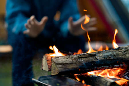 A man enjoying a bonfire in front of tentの写真素材