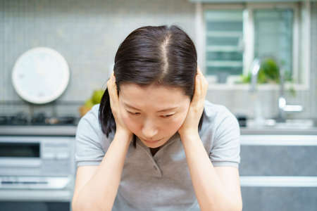 Asian middle aged woman with a tired look in the roomの写真素材