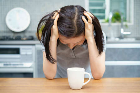 Asian middle-aged woman suffering from headache in the room