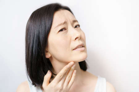 Middle-aged woman touching her face and suffering from skin problemsの写真素材