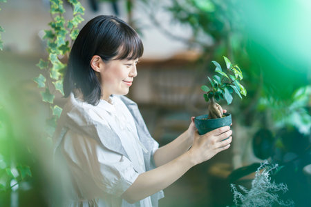 A young woman looking at the foliage plants with a smileの写真素材