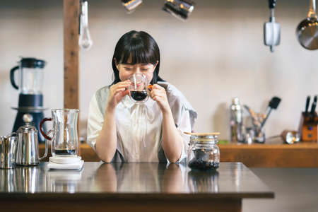 A young woman brewing and drinking coffee in a calm atmosphereの写真素材