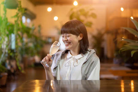 A young woman holding a glass of champagne in a warm atmosphereの写真素材