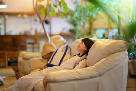 Young woman calming down on the sofa in the eveningの写真素材