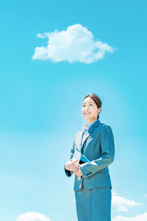 Young asian business woman standing against the blue skyの写真素材