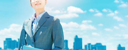 City center, blue sky and asian young business womanの写真素材