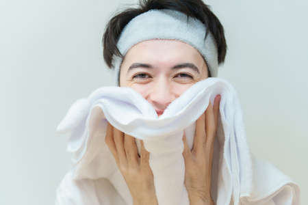 Asian young man wiping his face with a towelの写真素材