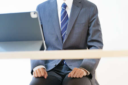 Asian man in a suit attending an online interview or meeting with a tense lookの写真素材