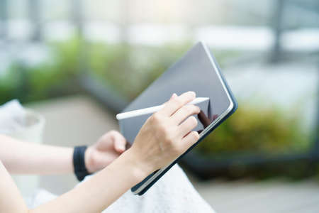 Female hand operating a tablet PC with a stylus penの写真素材