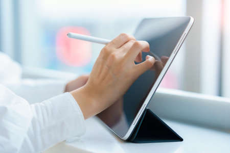 Female hand operating a tablet PC with a stylus penの写真素材