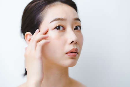 Asian young woman worried about skin conditionの写真素材