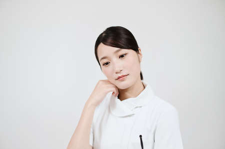 Asian woman in a worried white coatの写真素材