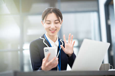 Asian young business woman talking to the screen of her smartphoneの写真素材