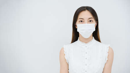 Young woman wearing a mask and white backgroundの写真素材