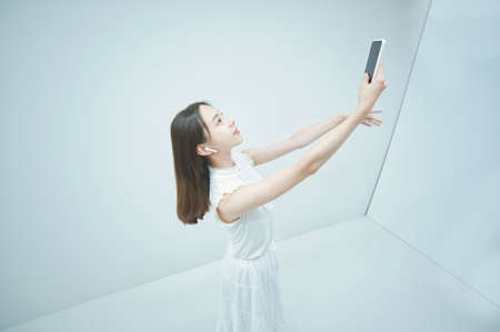 Asian young woman dancing while holding a smartphoneの写真素材