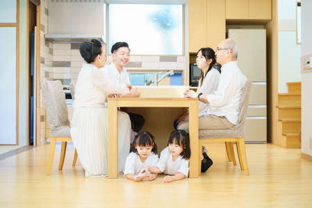 3 generations family gathering at the table in the roomの写真素材