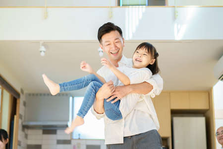 Little girl playing with dad in the roomの写真素材
