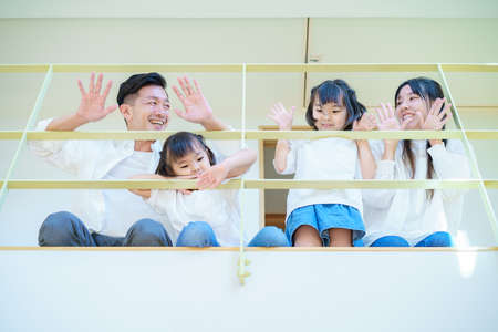 Family waving from the upper floors of a residential atriumの写真素材