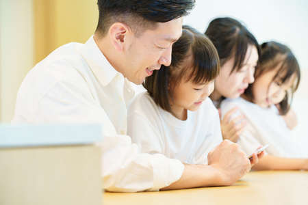 Parent and child looking at the screen of the tablet PC in the roomの写真素材