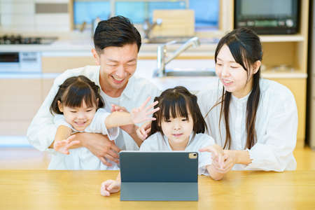 Parent and child looking at the screen of the tablet PC in the roomの写真素材
