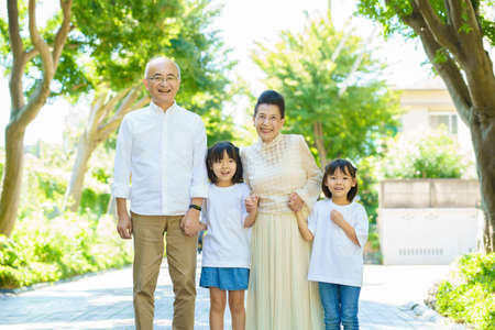 Senior couple taking a walk with their grandchildren in greenly streetの写真素材