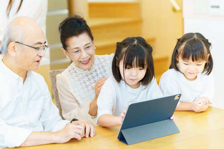 Senior couple and grandchildren operating tablet PC on the table