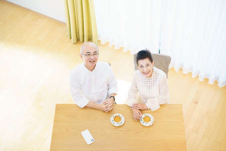 Senior couple chatting with smile in the living roomの写真素材