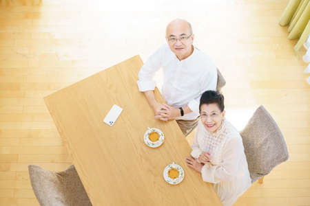 Senior couple chatting with smile in the living roomの写真素材