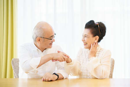 Senior couple chatting with smile in the living roomの写真素材