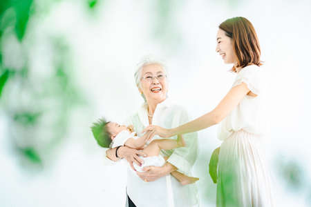 Senior women hugging babies and women watching overの写真素材